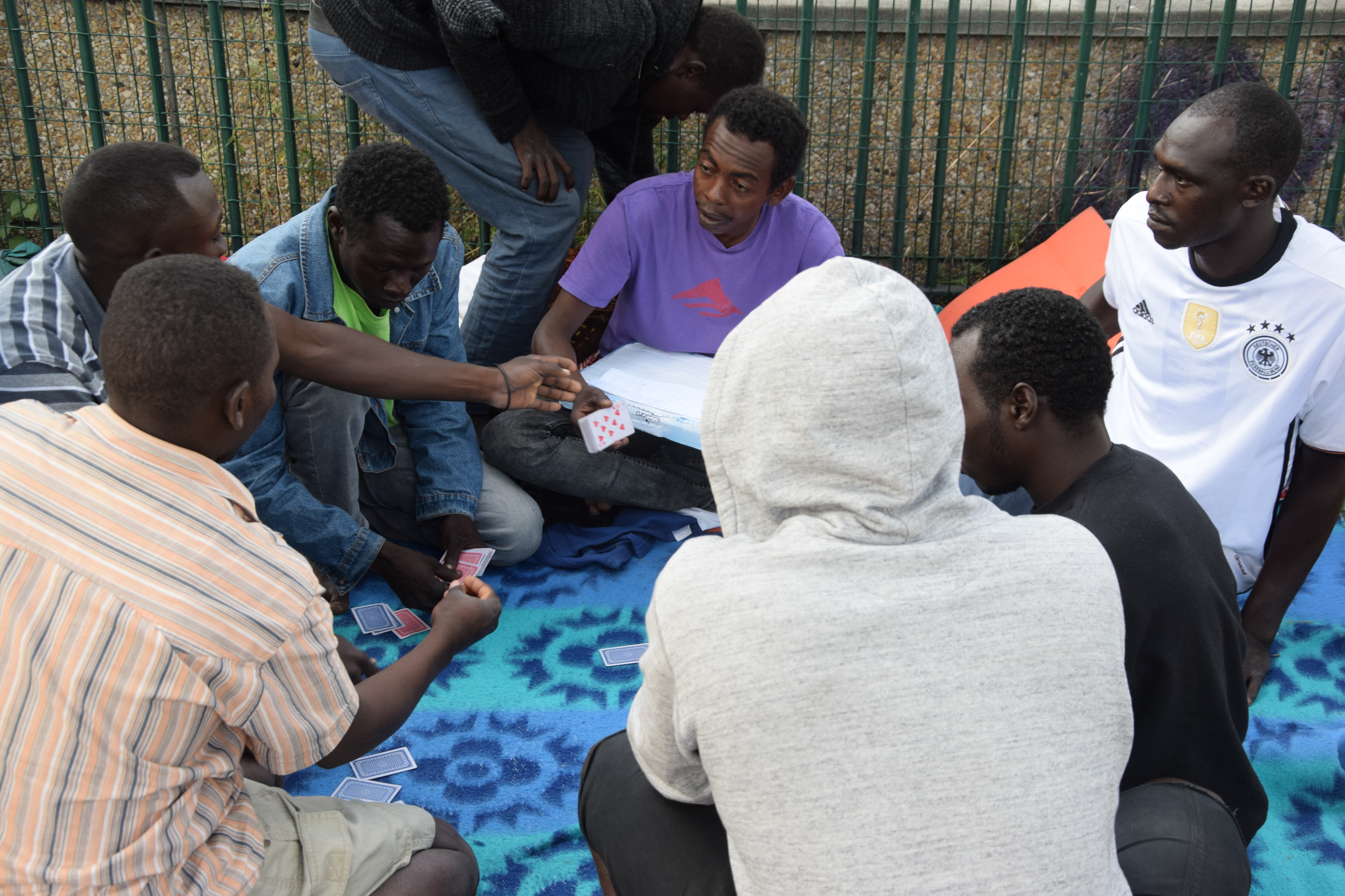 Migranti giocano a carte all’accampamento informale di Porte de la Chapelle, aspettando l'ora conclusiva del digiuno per il Ramadan (foto: Veronica Di Benedetto Montaccini)