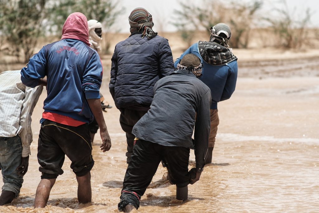 Migranti che attraversano un corso d'acqua dopo una tempesta, sulla rotta sahariana verso la Libia (foto: Giacomo Zandonini)