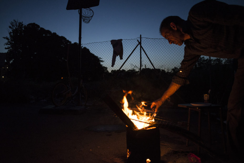 S. cuoce la cena su un pentolino da campeggio accanto alla tenda in cui ora vive con la compagna (foto: Federica Mameli)