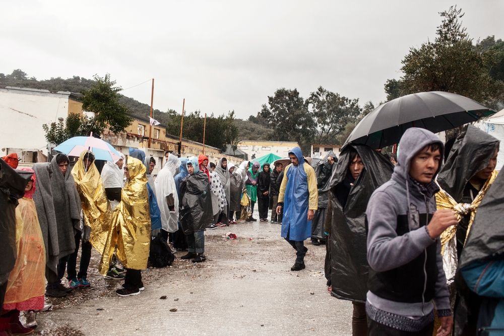 Refugees queue during a rain storm as they wait to be registered at the Moria Reception Centre in Lesbos, Greece
